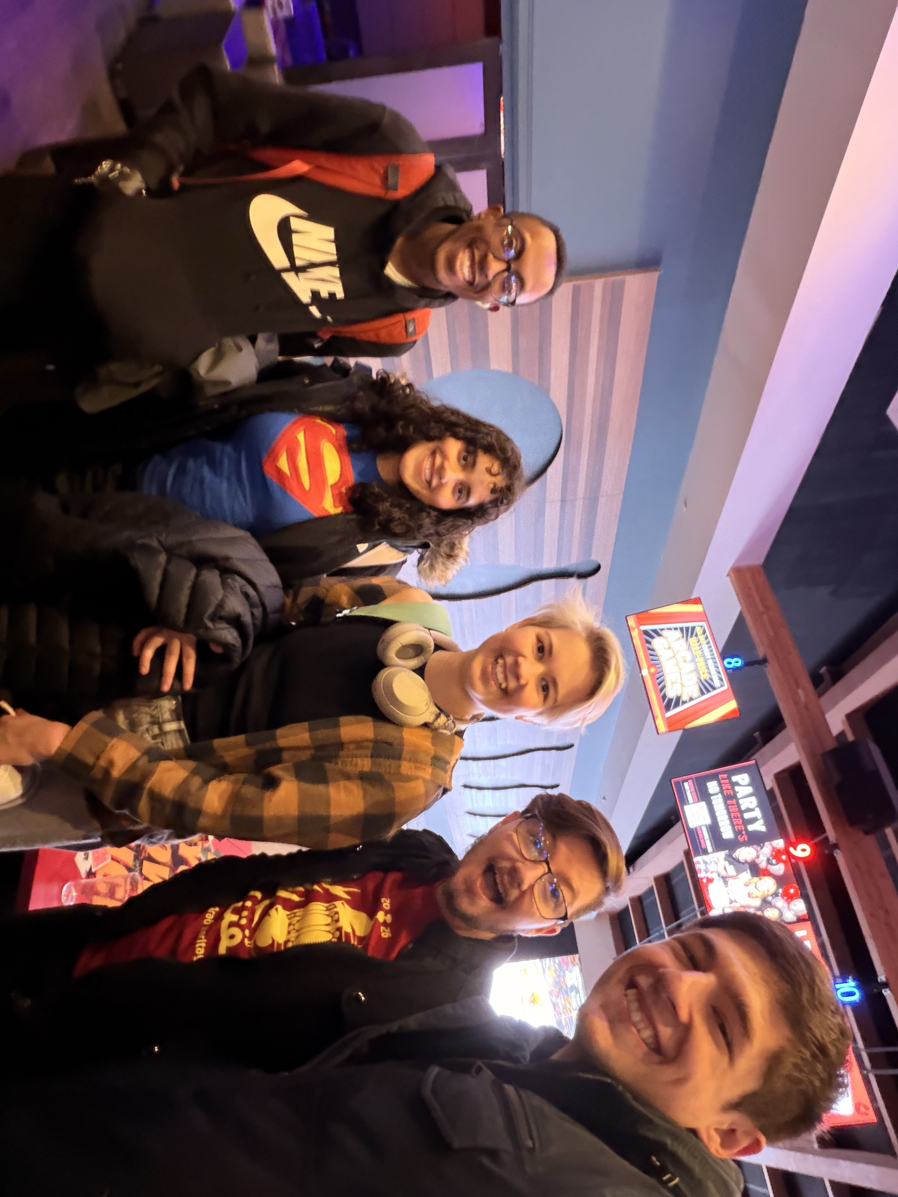 Gavin and friends smiling together at an arcade